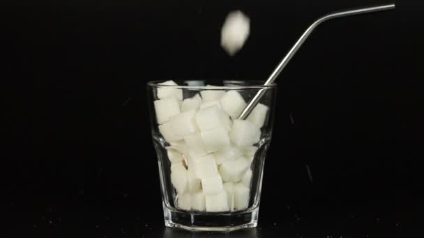 Szklane wypełnione kostek cukru białego symbolizujące Wysoka zawartość cukru w nasze napoje i dieta. — Wideo stockowe