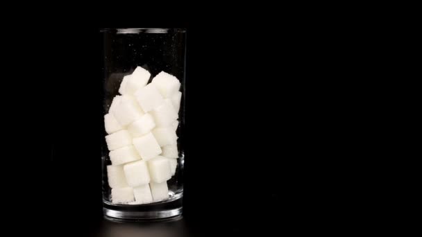 Стекло, наполненное кубиками белого сахара, символизирующее высокое содержание сахара в наших напитках и диете . — стоковое видео