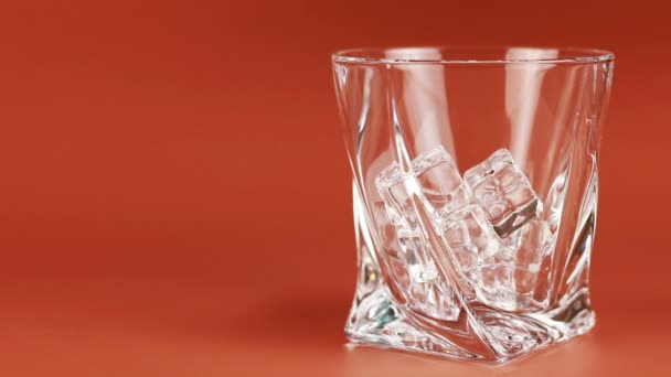 Whiskey wordt gegoten in glas met ijsblokjes — Stockvideo