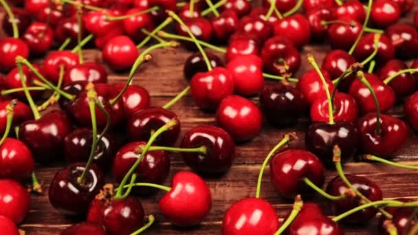 Fles van cherry wijn/nabij verspreide kersen op houten tafel — Stockvideo
