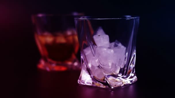 Whisky wird vor schwarzem Hintergrund in ein Glas gegossen. — Stockvideo