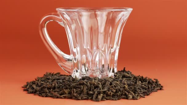 Té que se vierte en taza de té de vidrio sobre fondo marrón — Vídeo de stock