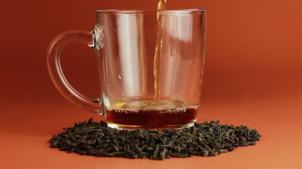 Tee wird in Glas Teetasse auf braunem Hintergrund gegossen — Stockvideo