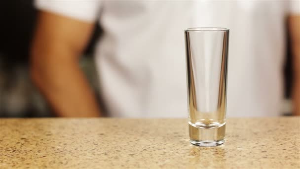 Barman vertiendo whisky en tres vasos de chupito con hielo — Vídeo de stock