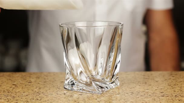Barman derramando uísque em vidro de tiro com gelo na mesa de bar — Vídeo de Stock