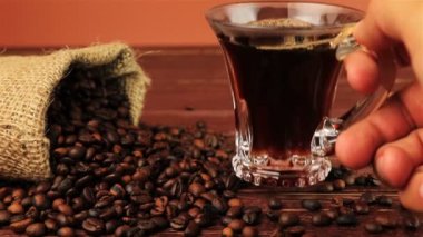 Genç adam koyar onu masada kahve fincanı kahve fasulye çuval bezi çanta kahverengi ahşap masa üzerinde yer alan