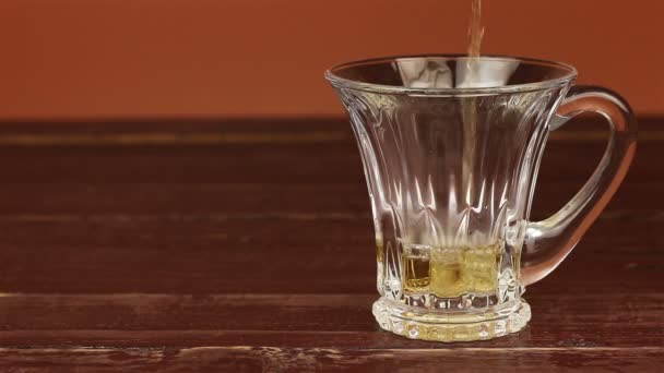 Tea being poured into glass tea cup on brown wooden table — Stock Video