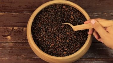 Kahve çekirdekleri kahverengi ahşap masa üzerinde ahşap kase tahta kaşık kullanarak alma