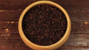 Kahve çekirdekleri kahverengi ahşap masa üzerinde bir kaşıkla karıştırarak bir ahşap plaka