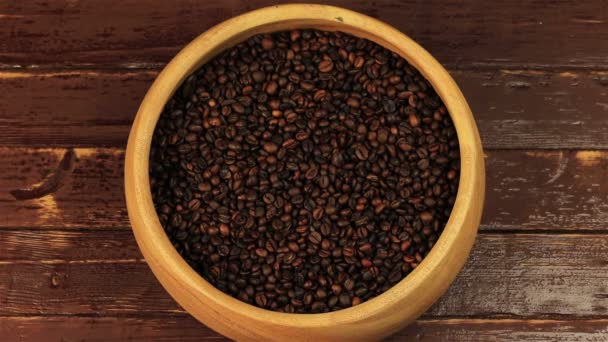 Coffee beans in a wooden plate stirring with a spoon on brown wooden table — Stock Video