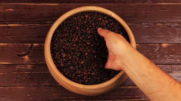 Grabbing coffee beans from a wooden plate on brown wooden table — Stock Video