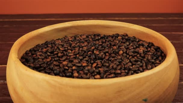 Coffee beans in a wooden plate stirring with a spoon on brown wooden table — Stock Video