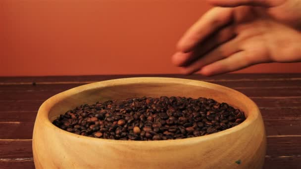 Agarrar granos de café de un plato de madera en una mesa de madera marrón — Vídeo de stock