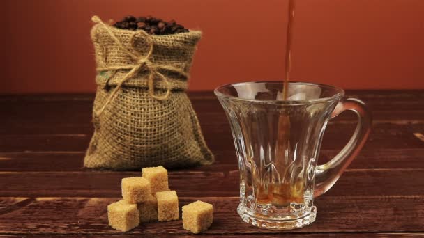 Öntés egy csésze kávé asztal található kávébab zsákvászon zacskó, barna cukor kockák barna fából készült asztal fölé