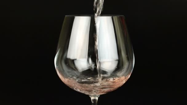 Vinho rosa derramando em vidro no fundo preto — Vídeo de Stock