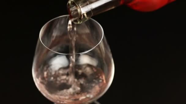 Růžové víno nalil do sklenice na černém pozadí — Stock video