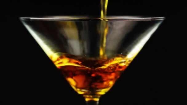 Verser un cocktail orange en verre de martini sur fond noir — Video