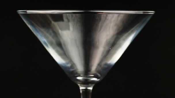 在黑色背景上的马提尼杯浇注棕色鸡尾酒 — 图库视频影像