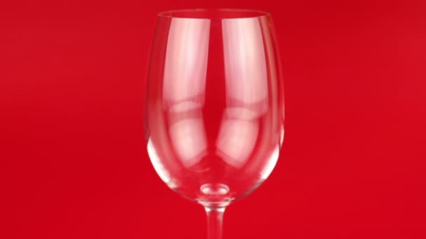 White wine poured into glass on red background — Stock Video