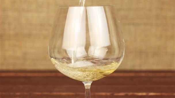 Vino blanco vertiendo en un vaso sobre una mesa de madera — Vídeos de Stock