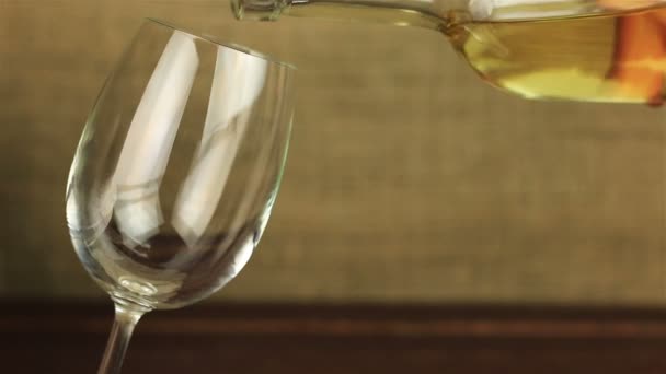 Белое вино, наливаемое в стакан на деревянном столе — стоковое видео