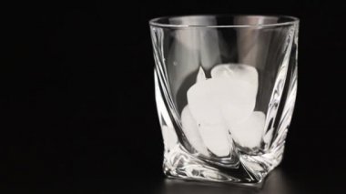 Bir bardak buz siyah bir arka plan ile içine dökülür varlık viski