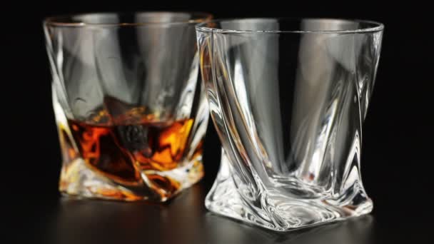 Whiskey wordt gegoten in een glas op zwarte achtergrond — Stockvideo