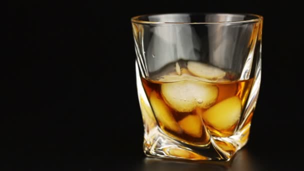 Young man drinking whiskey with ice over black background — Stock Video
