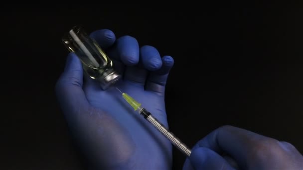 Injekční jehla prorazí gumovou zátku lahvičky a náplň stříkačku ze skleněné ampule na černém pozadí — Stock video