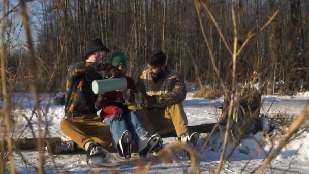 Молоді друзі вчаться кататися на замерзлому озері взимку. Пийте гаряче глінтвейн . — стокове відео