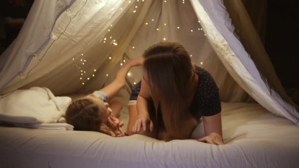 Gelukkig mam en dochter spelen met elkaar in een zelfgemaakte tent thuis ze lachen en knuffelen — Stockvideo