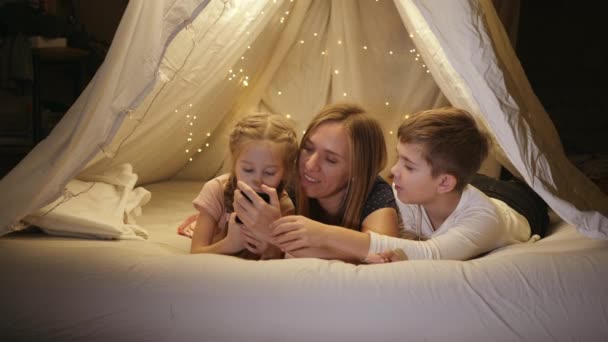 Щаслива мама з двома дітьми, переглядаючи фотографії на телефоні — стокове відео