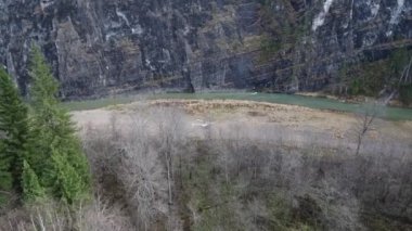 Pervaneli bir helikopter nehir kıyısında bir kayanın altında duruyor. Kuşbakışı bakış..
