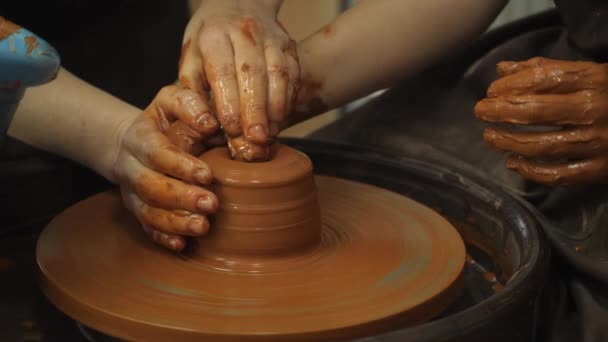 Close-up van volwassen en kinderen vuile handen gieten klei in keramische pot op gooien wiel werken binnen. Creatieve activiteit en traditioneel ambachtelijk concept. — Stockvideo