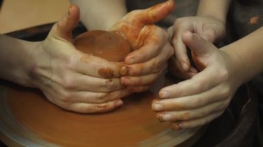 Bir çömlekçi çömlekçi, çömlekçi çarkında kilin nasıl düzgün tutulacağını gösterir..