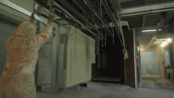 Dělník nakládá díly práškovou barvou postříkané do pece — Stock video