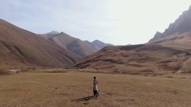 Un garçon et une fille marchent le long d'une gorge dans les montagnes du Caucase en se tenant la main. Clip Vidéo