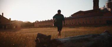 Drone operator controlling unmanned aerial vehicle near monastery during golden hour landscape