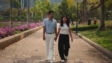 Young man and woman in love walking together on a path in a public park during a romantic date