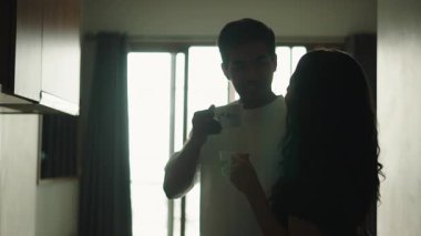 Happy young couple drinking coffee and talking together in their kitchen in the morning