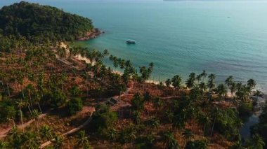 Pristine wai chaek shoreline on koh chang, revealing lush palms, crystal turquoise waters, solitary anchored boat against serene tropical landscape