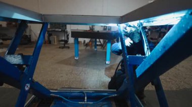 Endüstriyel bir fabrikada parlak kıvılcımlar saçan metal bir çerçeveyi kaynak yapmakta usta bir işçi - 4K Yatay