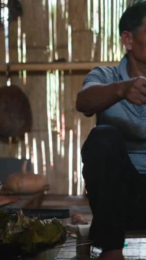 Üst düzey bir adam geleneksel yemekleri hazırlıyor ve yiyor tahta zeminde, FullHD dikey bir kırsal evde oturuyor.