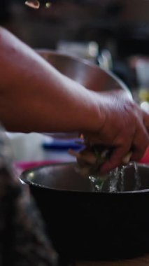 Asyalı bir kadının ellerinin yakın çekimi yerde oturup bir kasede sebzeleri yıkıyor - FullHD Dikey