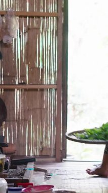 Güneydoğu Asyalı kadın geleneksel bir mutfak olan FullHD Dikey Mutfak 'ta bir tepsi taze çay yapraklarını dikkatlice yerleştiriyor.