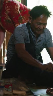 Asyalı bir adam baharatlı eti muz yapraklarına sarar ve basit bir mutfakta geleneksel bir yemek hazırlar.