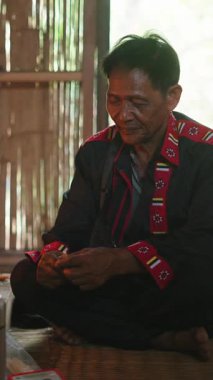 Ahşap bir konutun içinde otururken çıplak ayakla sigara yakan yaşlı koridor adamı.