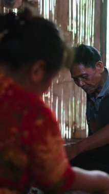 Lahu kabilesinden çıplak ayaklı yaşlı bir çift kırsal alanda bambu evlerinde geleneksel bir şekilde yemek pişiriyor.