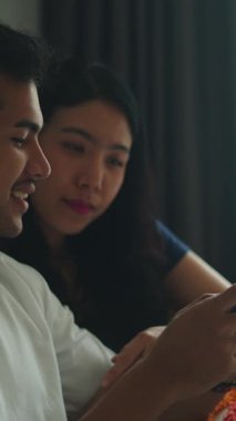 Mutlu genç bir adamla kadının yatak odalarında rahatlarken ve akıllı telefon kullanırken yakın çekim.