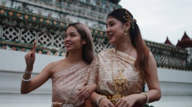 Geleneksel Tayland elbisesi giymiş, tapınak mimarisine hayran olan ve Tayland kültürünü keşfeden iki kadın.